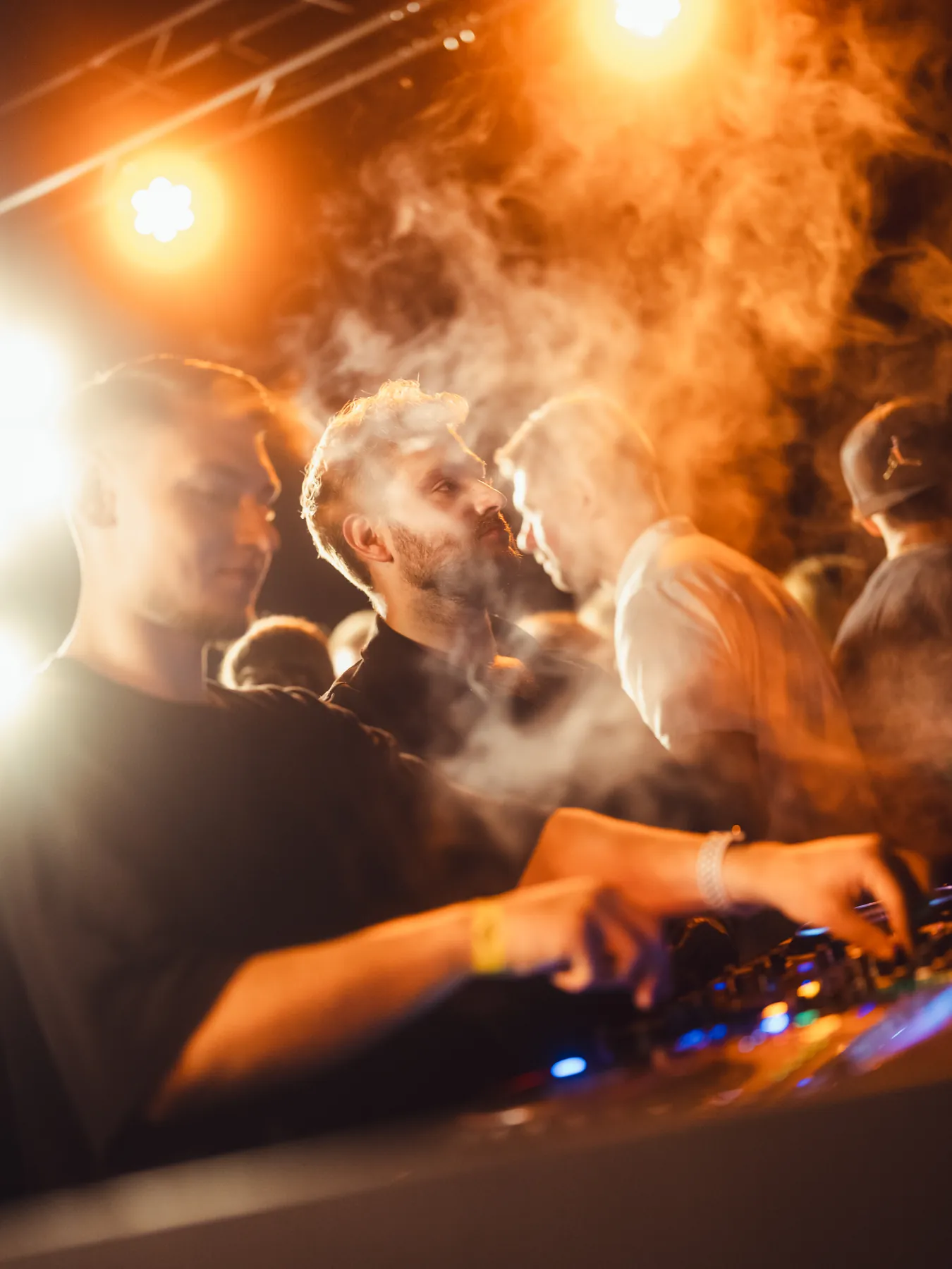 DJ za konsoletą w&nbsp;dymie i&nbsp;ciepłym świetle